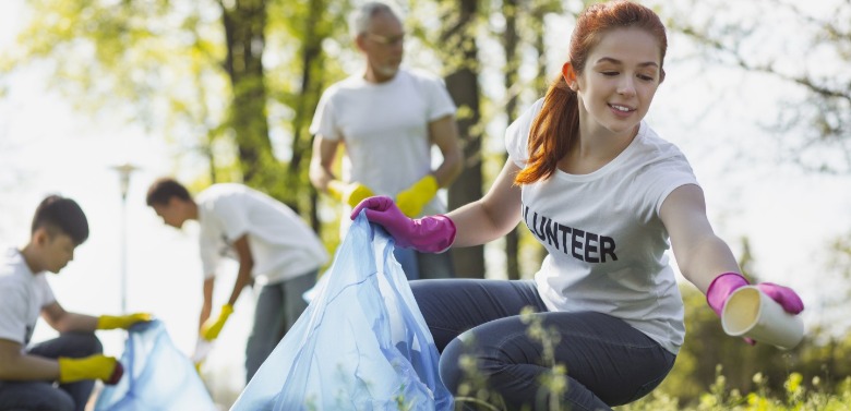 young woman volunteering by cleaning up outdoors | SeaShore Realty