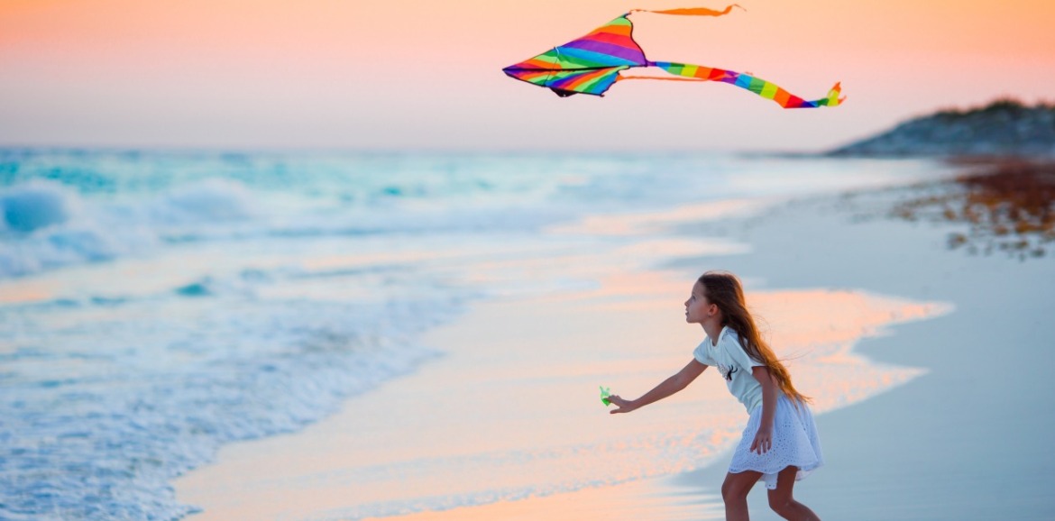 young girl flying kite on the beach | SeaShore Realty