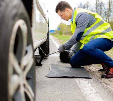 man changing tire alongside the road | SeaShore Realty